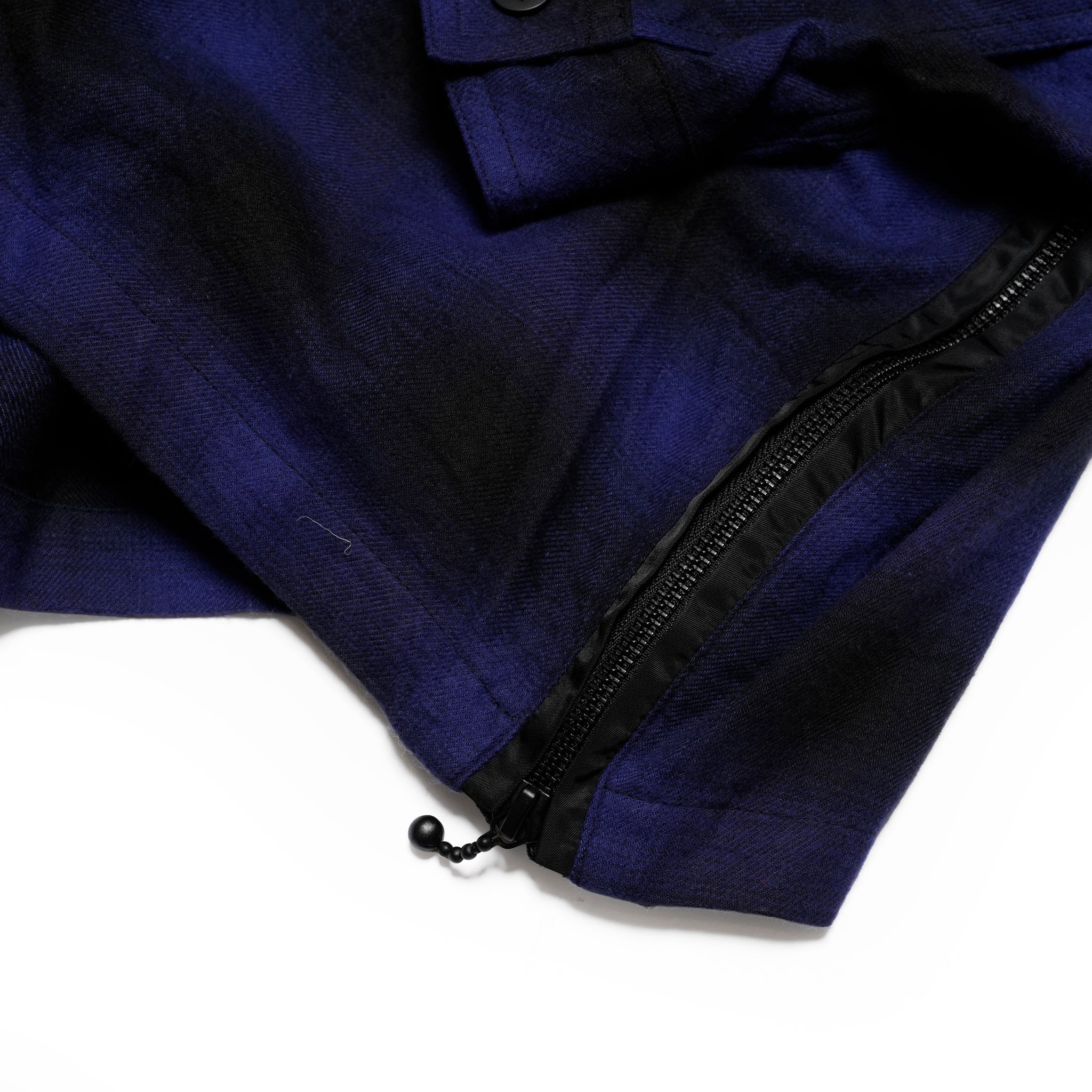 VIRGOwearworksのチェックシャツの裾サイドファスナー部分。ナイロン切替とジップデザインがアクセントになったディテール写真。
