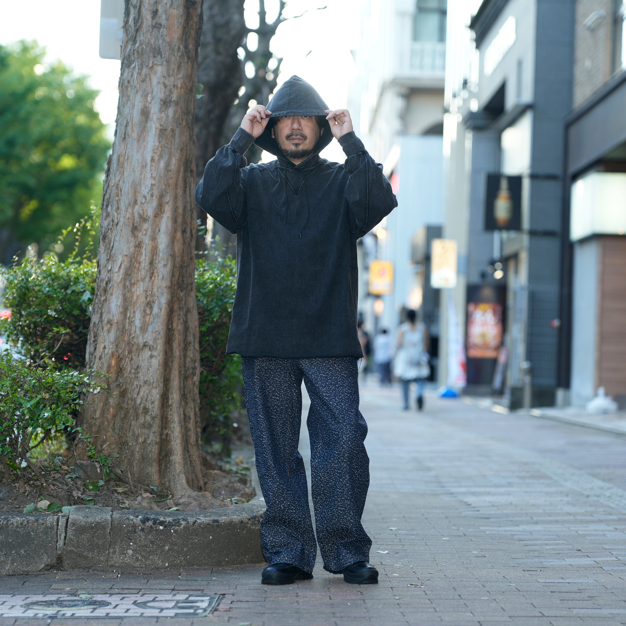 空紡糸で仕立てたTシャツ素材の軽量フーディー。ビンテージ感ある黒の褪せ感と立体フードが特徴。
